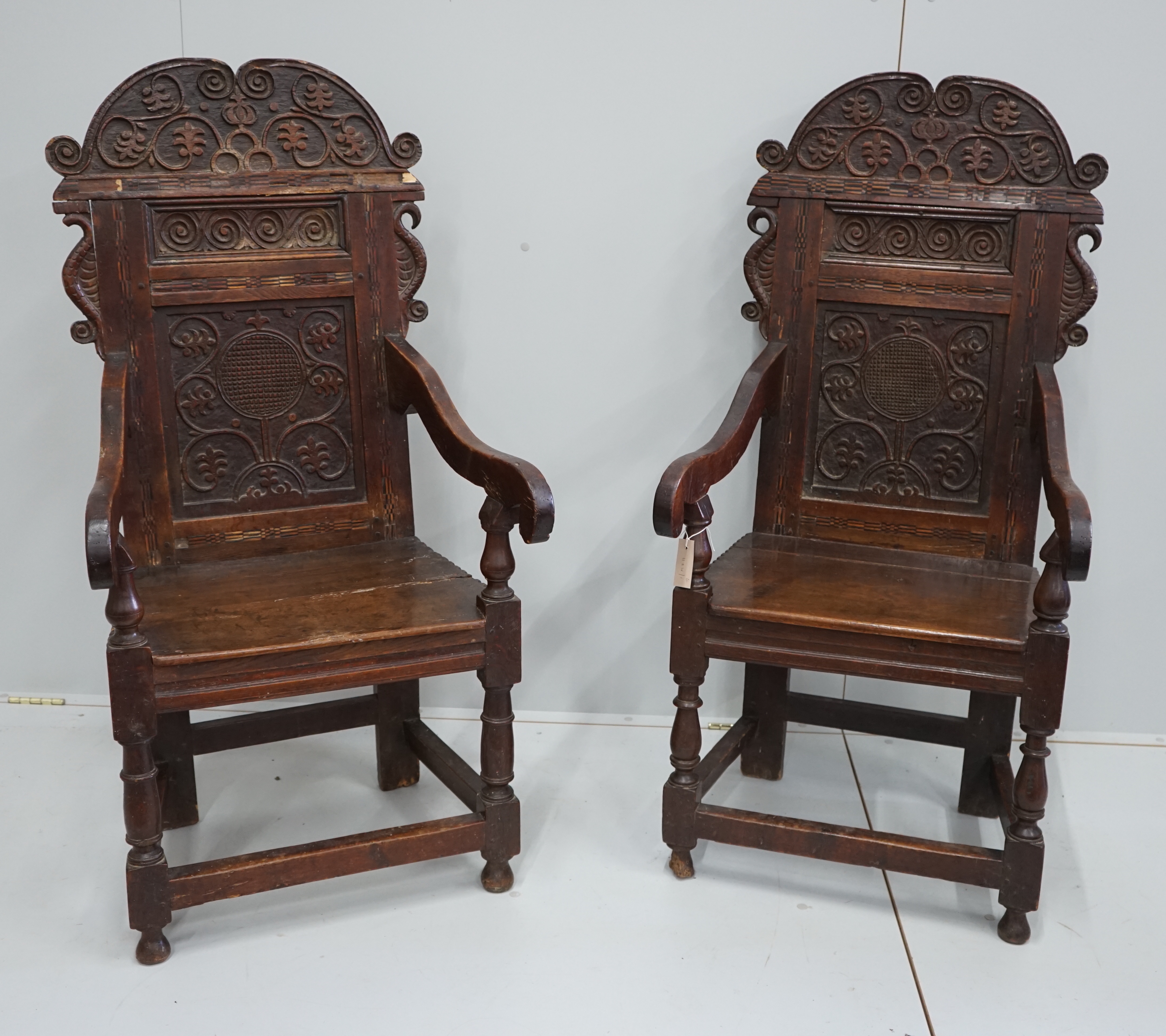 A pair of 17th century style inlaid panelled oak wainscot chairs, width 57cm, depth 40cm, height 121cm